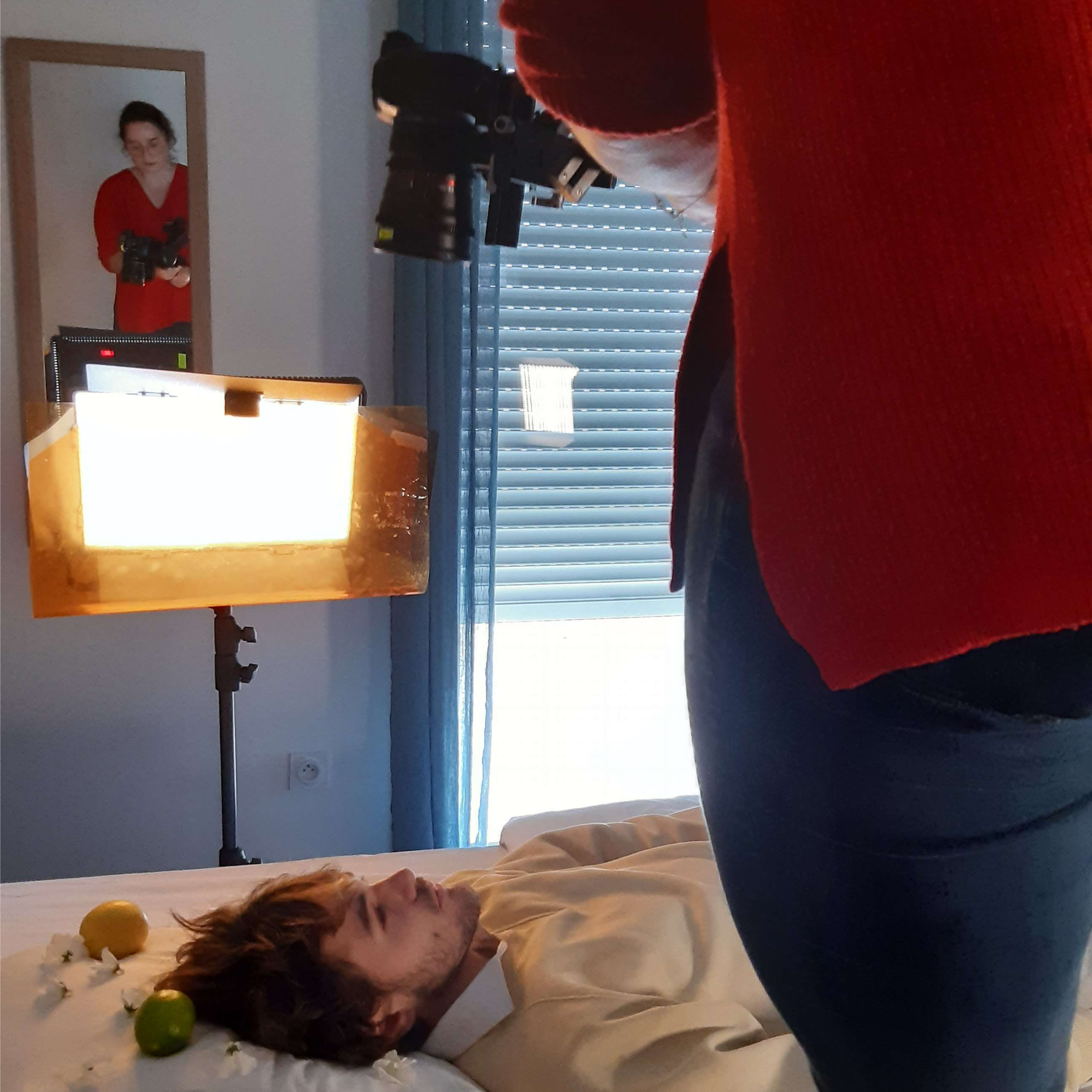 Photo de tournage : Margot debout sur le lit au-dessus de Louis pour filmer la première scène de la vidéo.