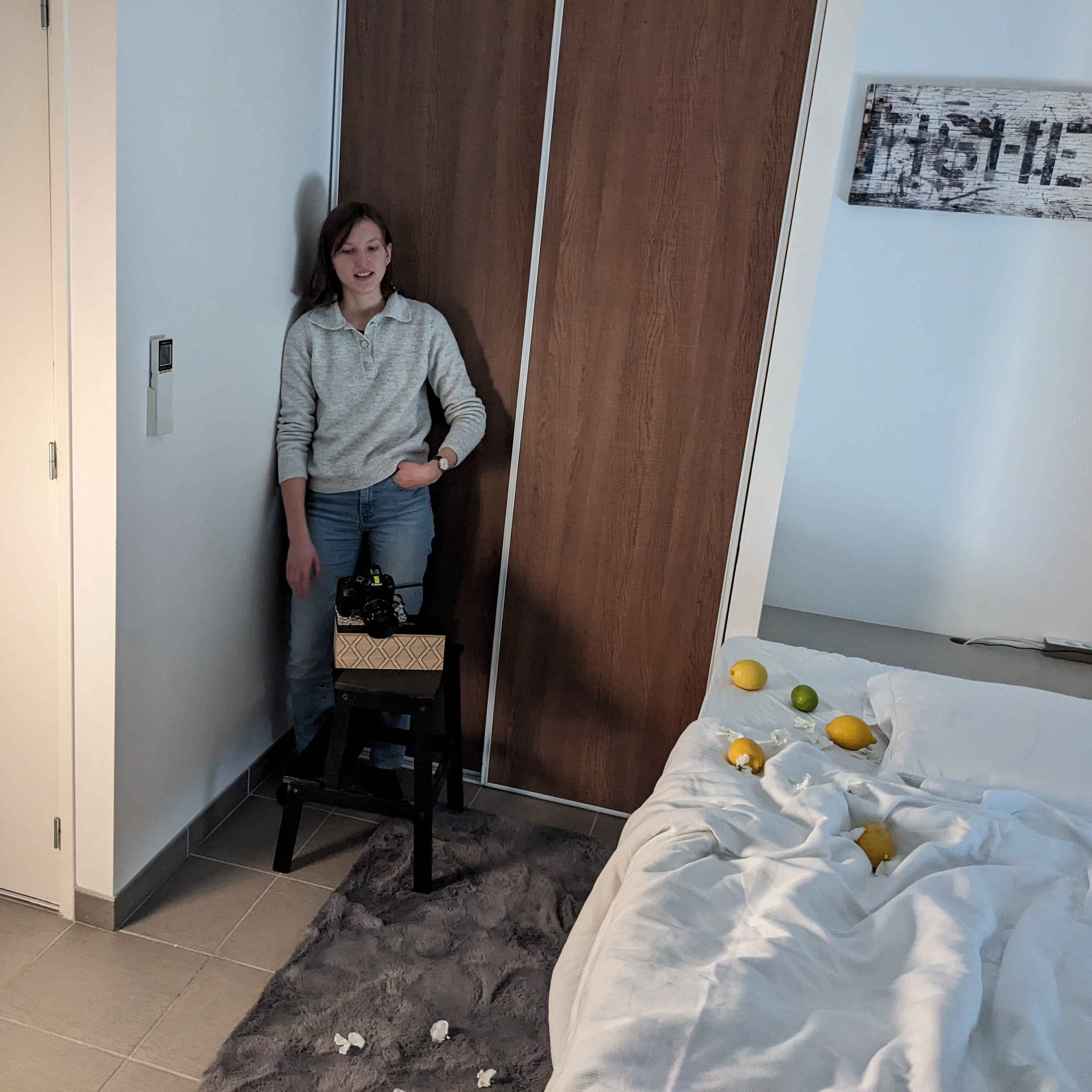 Photo de tournage : Lucie debout derrière l'appareil photo installé sur un support de fortune pour avoir le bon angle pour filmer la chute des citrons.